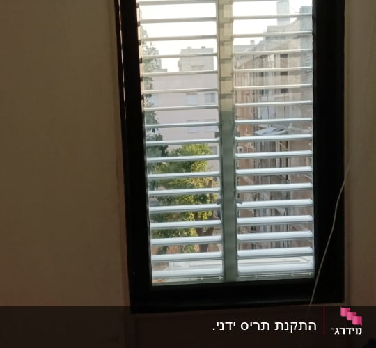 תריסי אלומיניום בחלון עם נוף עירוני